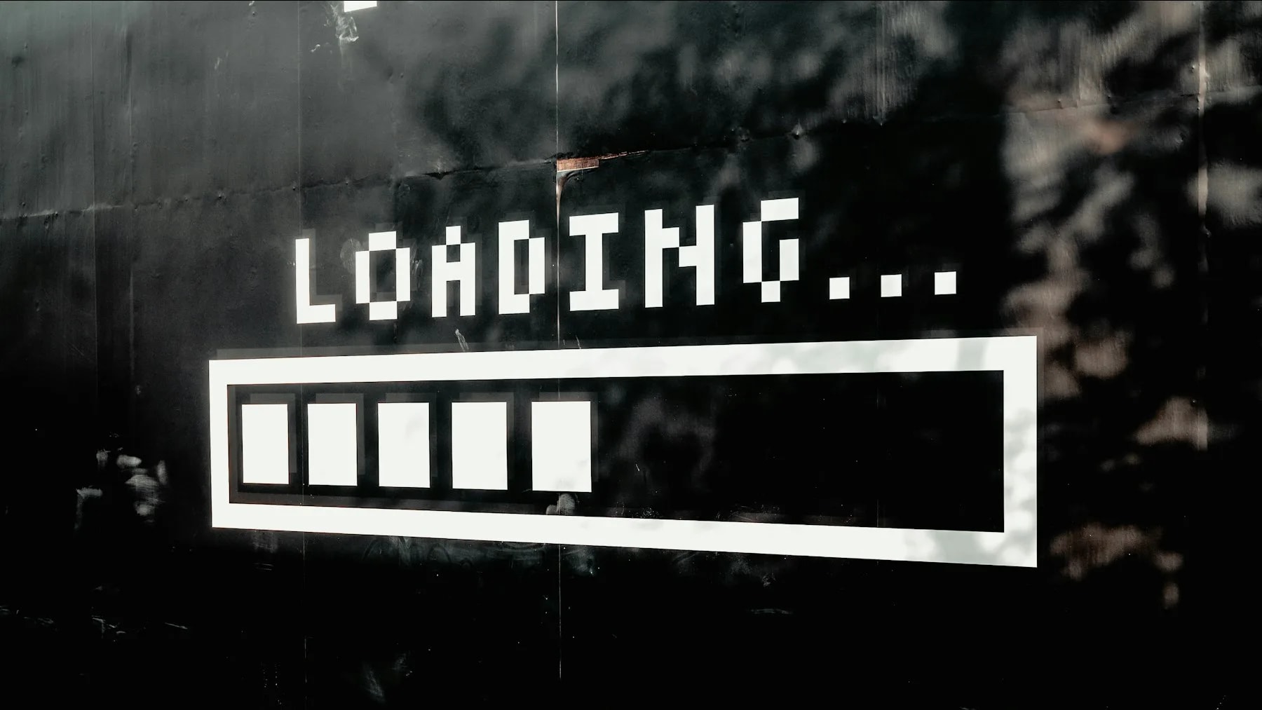A white loading bar with five filled segments on a black wall