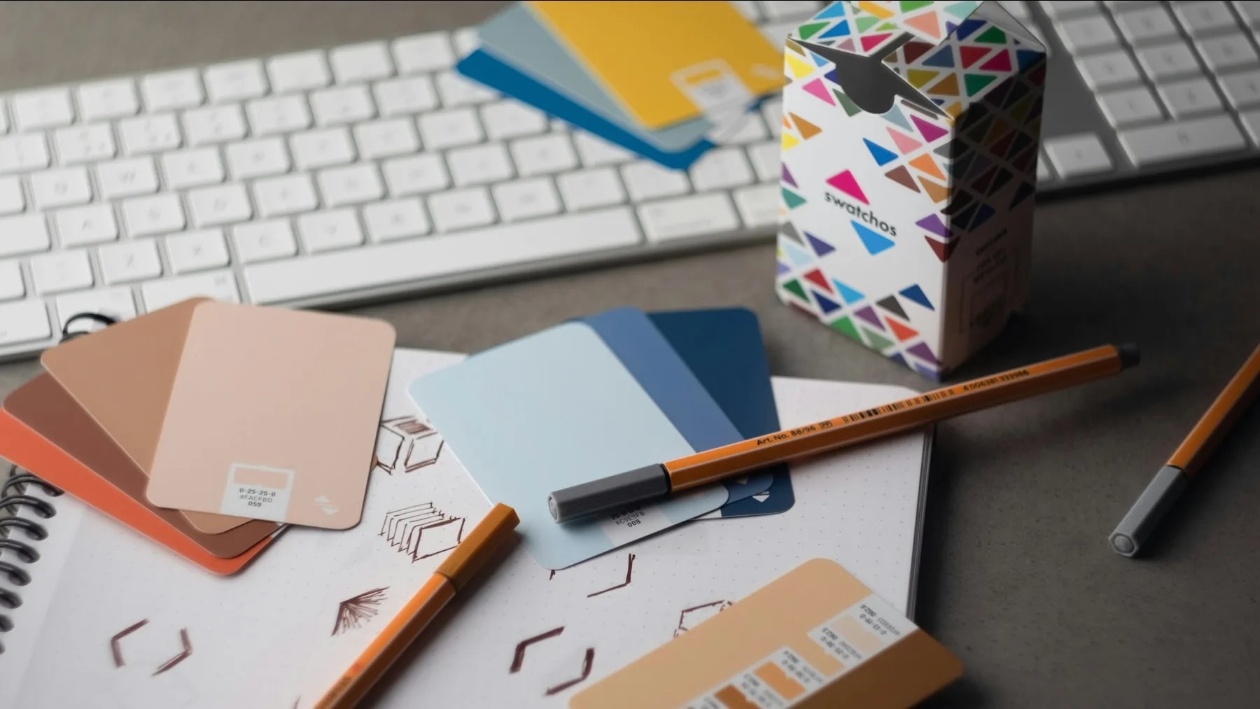 a desk with a keyboard, pencils, and various color samples
